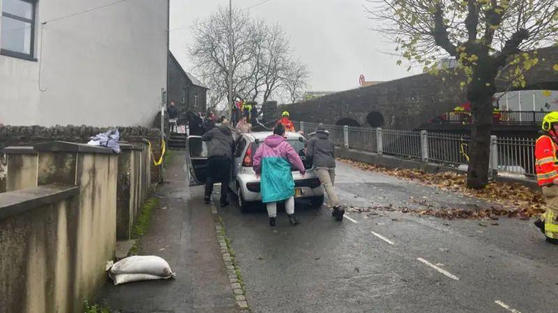 People push a car up a hill away from the floods in Pontypridd.