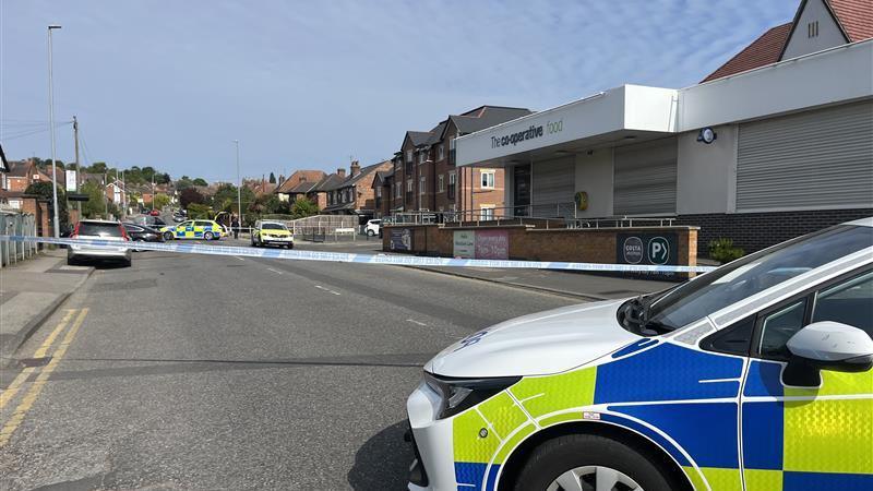 Police tape blocking the road near a supermarket