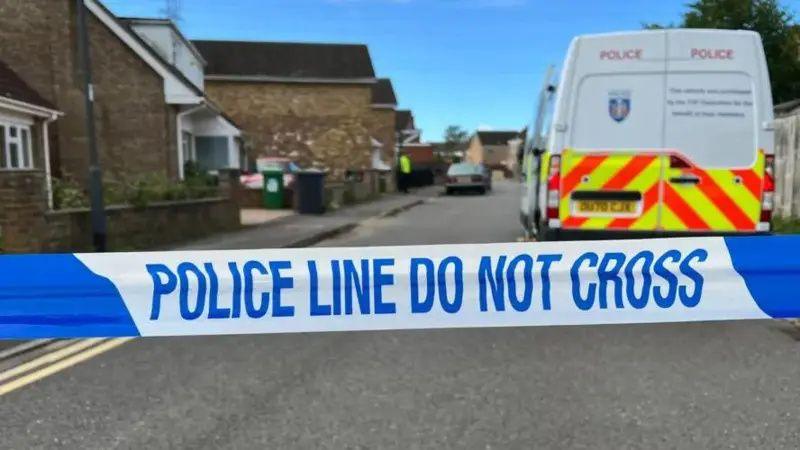 'Police line do not cross' tape across a street with a police van in the background.