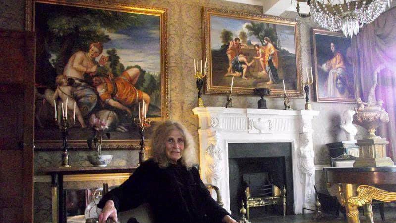 Cornelia Bayley, sitting in her ornately decorated drawing room, filled with paintings, candelabras and a chandelier