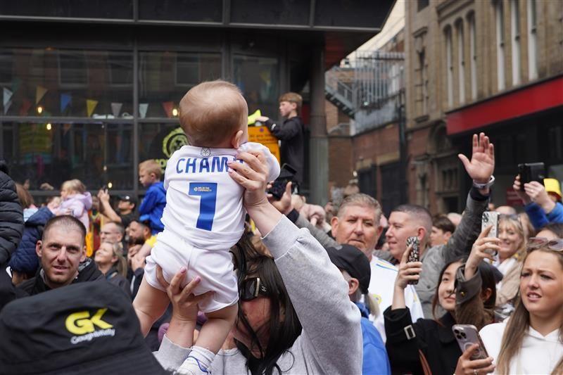 Fans hold up a baby wearing a Leeds United shirt 