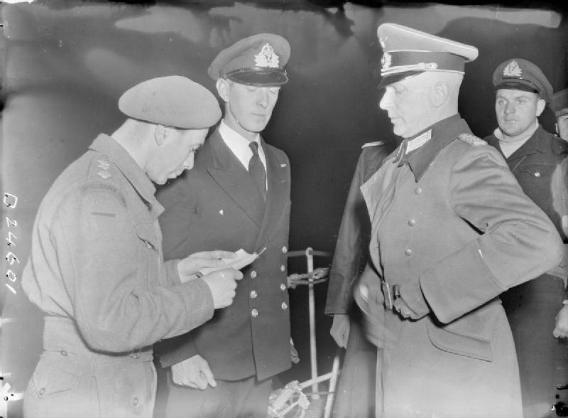 A black and white photo, showing General Major Siegfried Heine, the German Commander-in-Chief of the Channel Islands, having his papers check onboard HMS Bulldog.