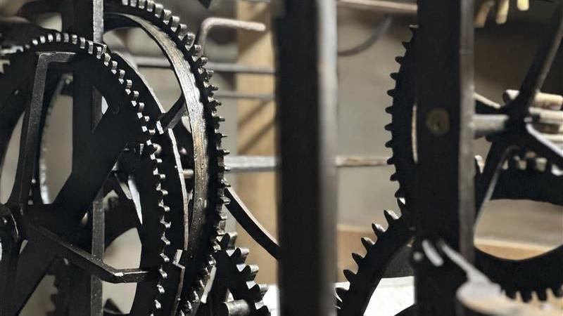A close up photo of various cogs in an antique clock mechanism.