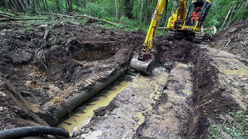 A digger removing earth around a water pipe