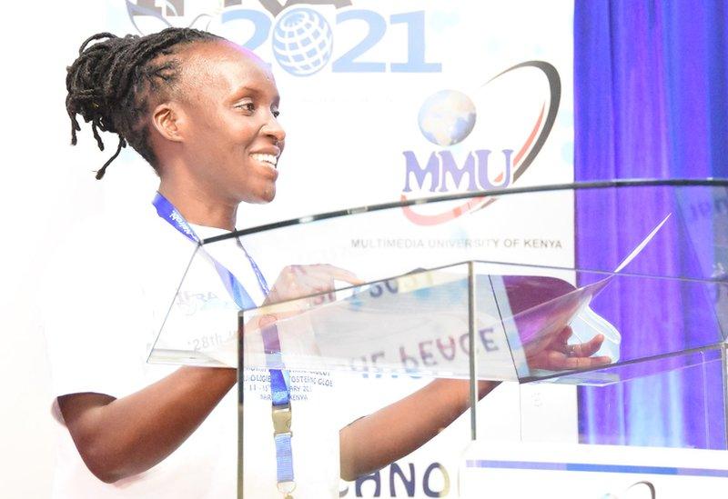 Dr Gladys Nyachieo standing at a lectern at a Multimedia University event.