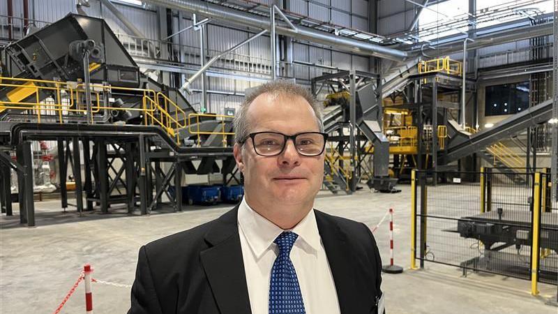 Paul Odendaal, the Development Engineer responsible for setting up the expanded copper recycling plant in Northfleet. Paul is wearing a black suit, blue patterned tie and a white shirt. The plant can be seen in the background of the image.