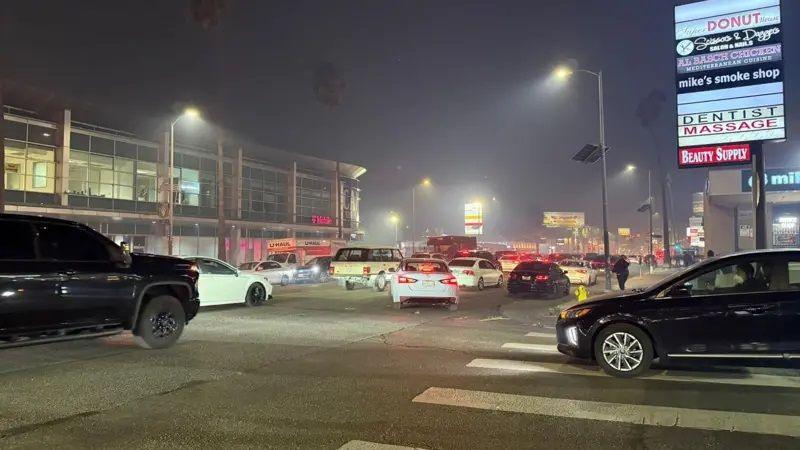 Several cars lined up on a road near the blaze. 


