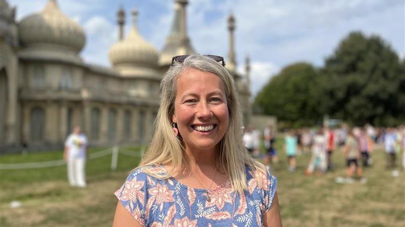 Jody East, museum curator, standing in front of the Royal pavilion in Brighton near to where the exhibition will be. She is wearing a floral top and smiling at the camera