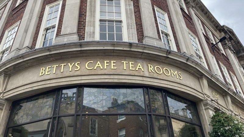 A gold sign for Bettys Cafe and Tea Rooms above glass windows