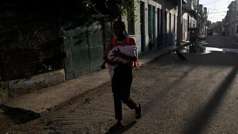 A woman walks with a baby as Cuba begins efforts to restore power after its grid collapsed in Havana, Cuba on 22 March, 2026. 
