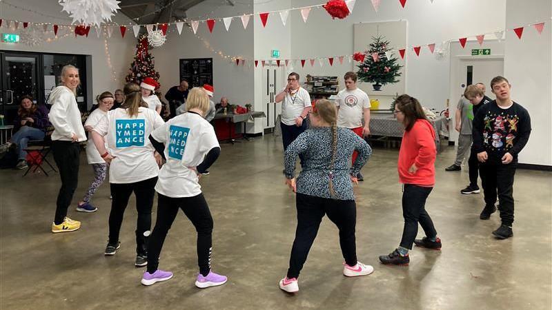 A group of people, most with their hands in on their hips. Most are looking away from the camera. 