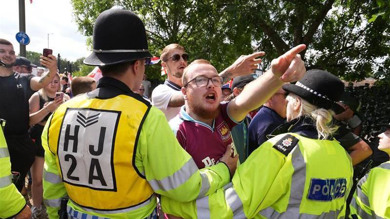 A man is held back by police.