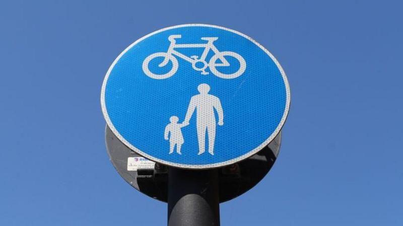 a close-up stock image of a blue circular road sign with a white cycling symbol above a white pedestrian symbol.