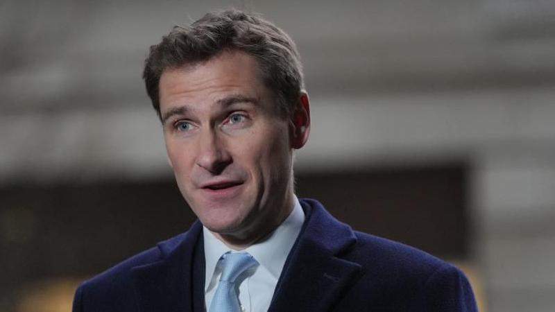 A man with short hair wearing a blue jacket, white shirt and light blue tie
