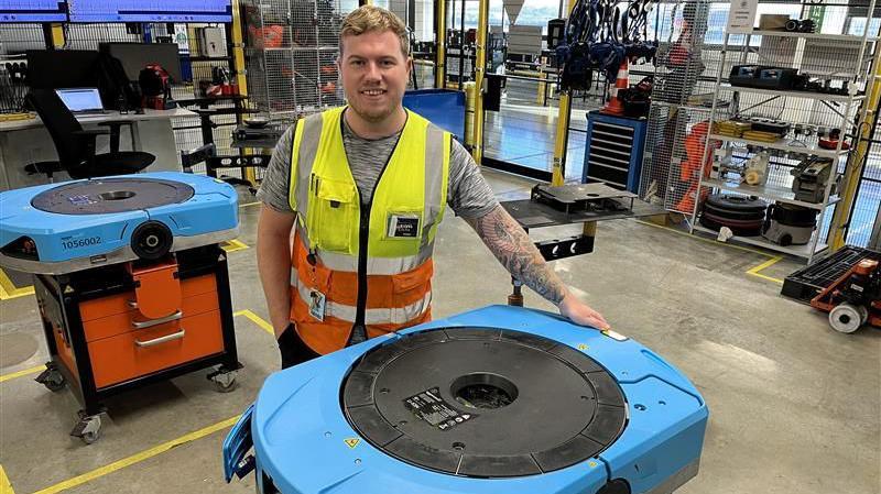 Aaron Bourne from the engineering department at Amazon's LCY3 depot in Dartford with two Hercules Drive robots