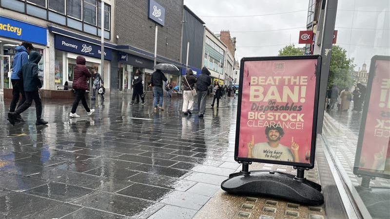 A sign for disposable vape sale on a damp Leicester street