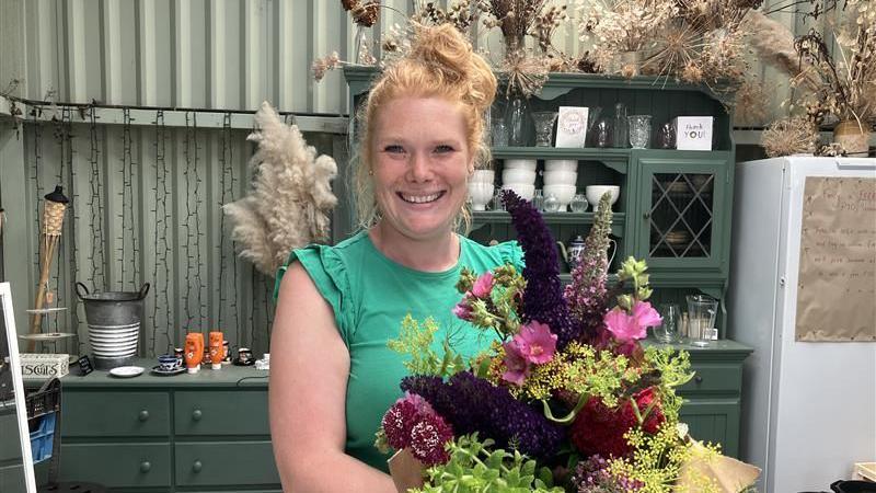 A woman smiles widely holding a bouquet of flowers. 