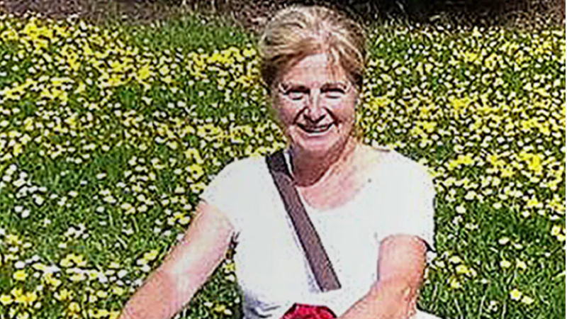 Danielle Carr-Gomm wearing a white t-shirt, standing in front of a flowery meadow