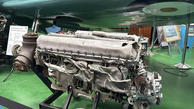 The large grey Spitfire engine which is mostly intact. There are some dents to the exhaust system and a small gash in the top cylinder where the oil leaked out. The propellers at the front also still have some of the wood from the propellers.