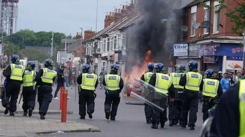 Riot police in Middlesbrough during the summer riots. A property is on fire.