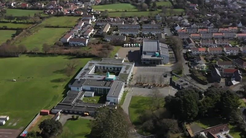 An aerial view of a school campus and fields behind.