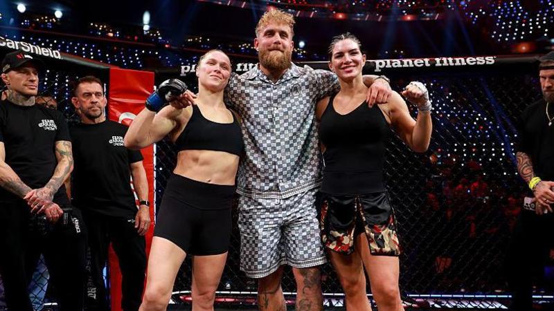Jake Paul stands in between Ronda Rousey and Gina Carano