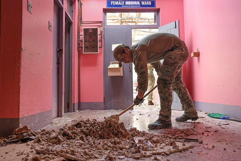 Soldier pushes debris in pink hospital hallway