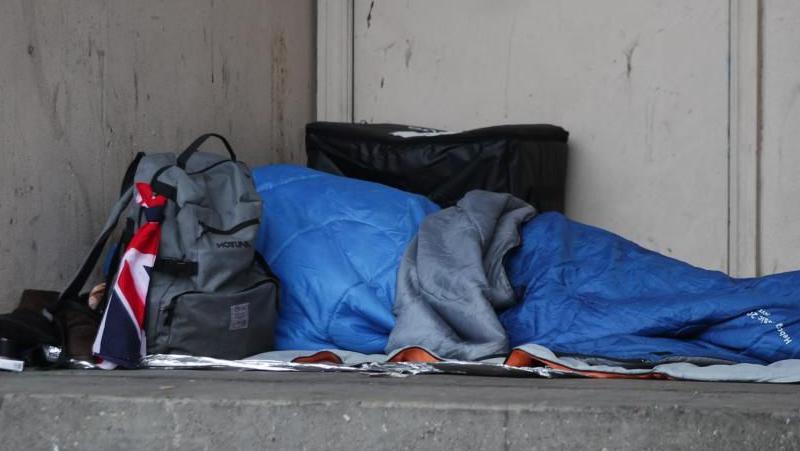 Man in blue sleeping bag in doorway