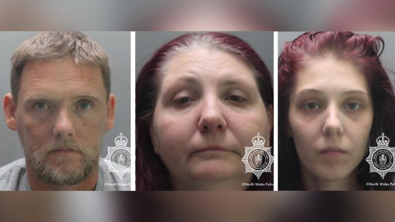 Three police mugshots side by side. The left is of a man with short brown hair and a beard. The middle and right are of two different women, both with long dyed-red hair.