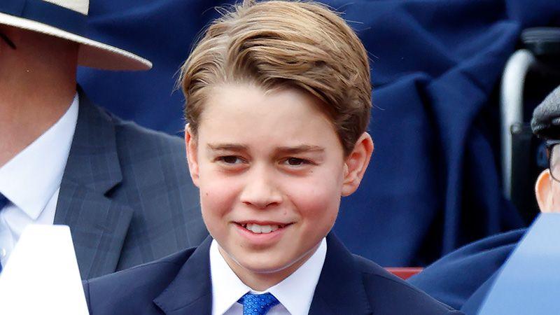 Prince George sits alongside others in a blue suit with white shirt and blue tie