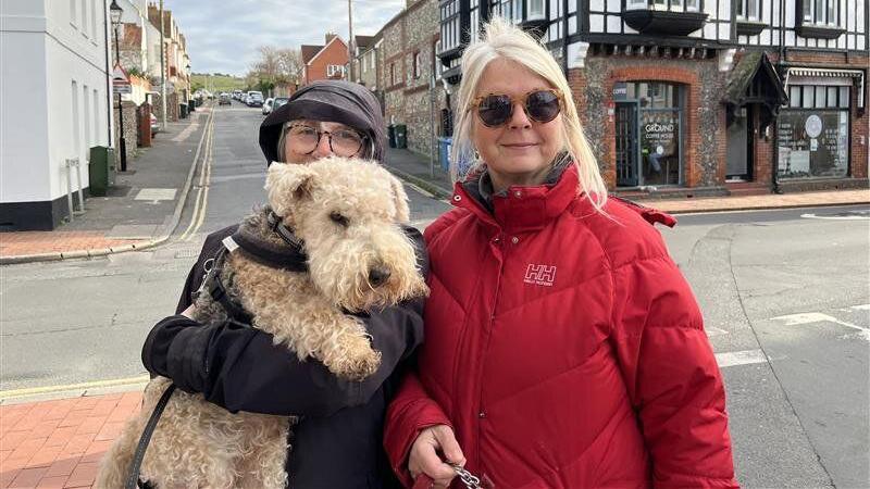 Dawn Jones (left) wearing a purple hat and coat covering her face with a brown dog and Siobhan Dodds (right) wearing a red coat, sunglasses and having blonde hair.