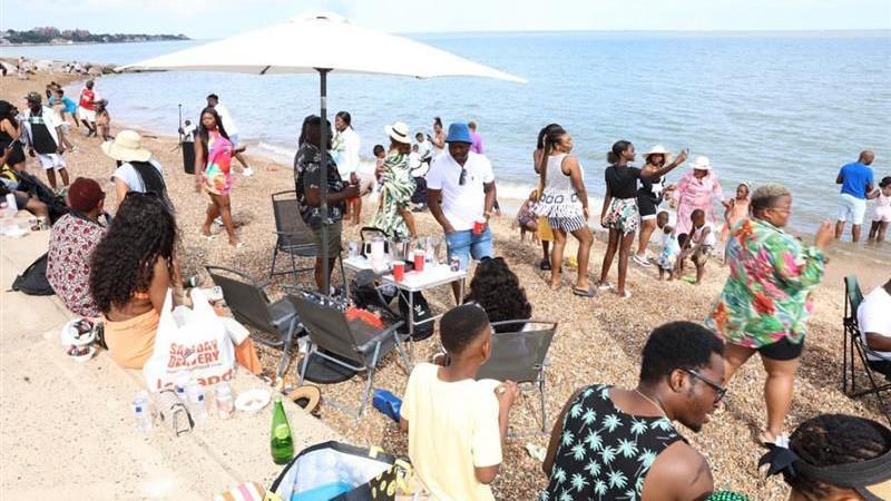 People talk and enjoy time on Felixstowe beach. 