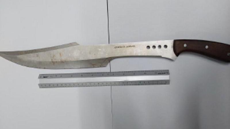 A large kitchen knife with a brown handle and a curved, metal blade, which shows signs of wear and discolouration. It is shown next to a 30cm ruler and is almost twice as long