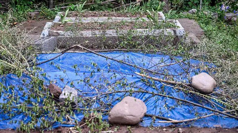 The grave of the twins. A blue plastic sheet is spread over their grave.