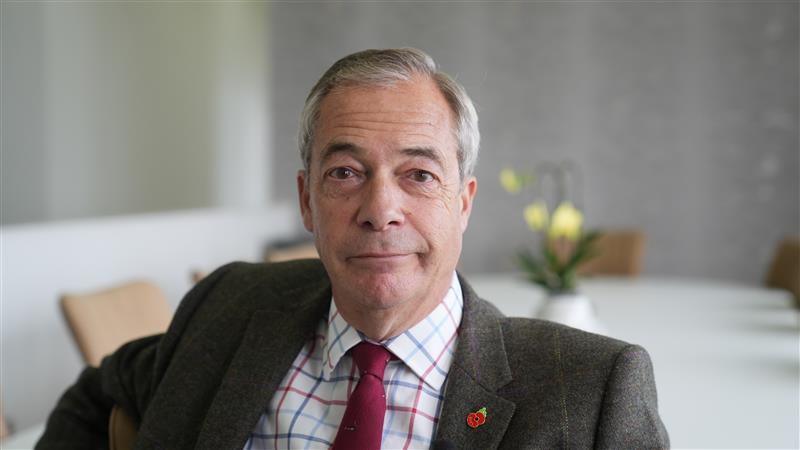 A man in a suit with a poppy pin and a purple tie smiling at the camera