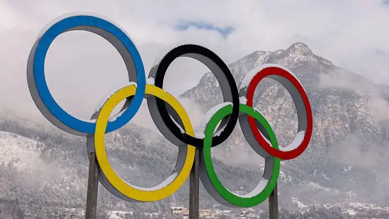 The Olympic rings with a snowy mountain in the background