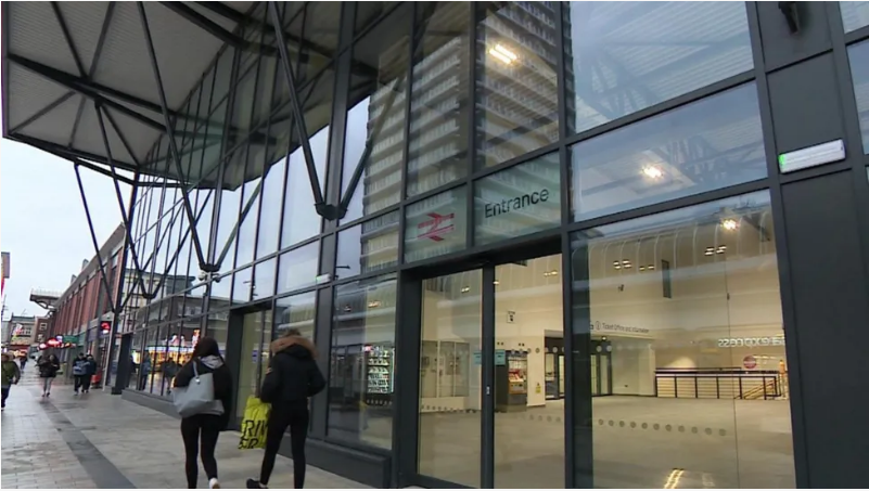 The front of Sunderland station which shows a long concourse of windows and glass and a number of people walking by.