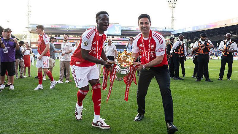 Bukayo Saka and Mikel Arteta celebrate with Premier League trophy