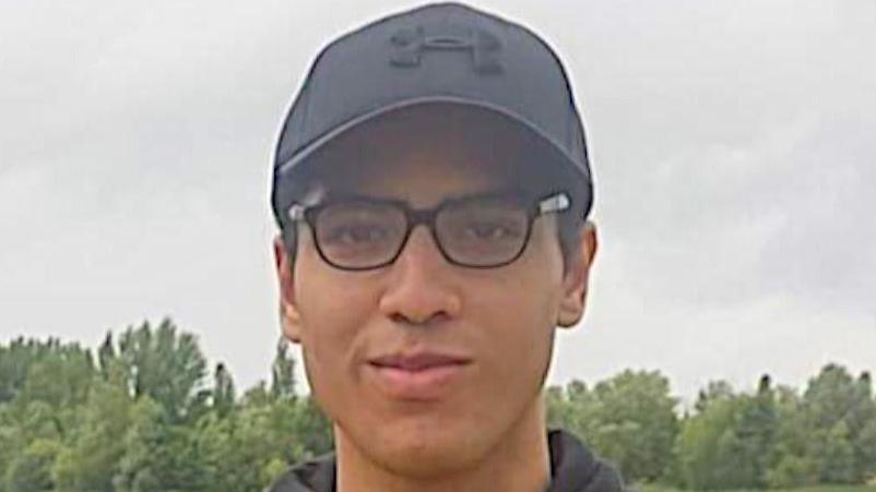 Nicholas Prosper dressed in glasses, a black baseball hat and yellow and black hoodie