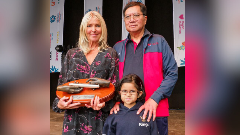 Lisa Wilson posing for a picture with organ recipients Gordon and Fatima. Mrs Wilson is holding Tom's Baton.