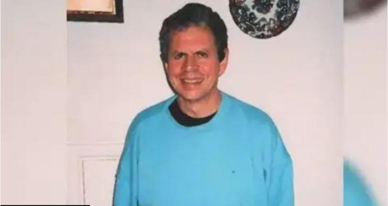 A man, Stephen Ridgeway, is smiling at the camera and wearing a blue jumper. He has short dark grey hair.