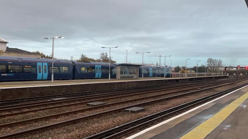 Empty train lines at Paddock Wood station, as seen from the platform. In the background there's a blue Southeastern train on a different platform.