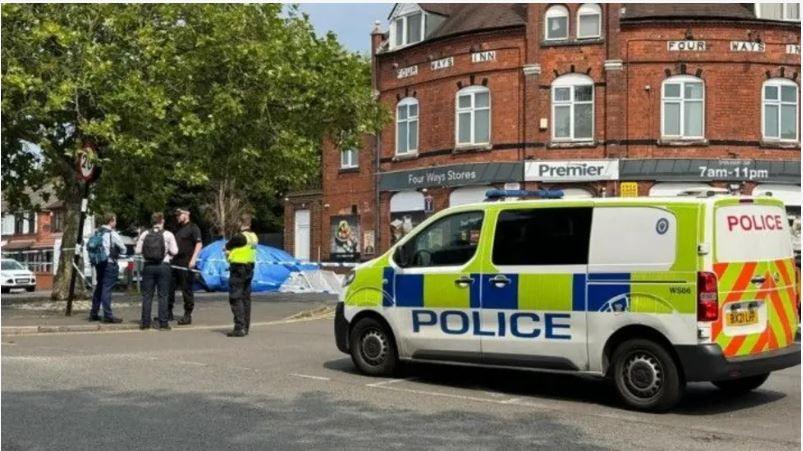 A police van and crew at the scene near a car covered with a blue plastic sheet