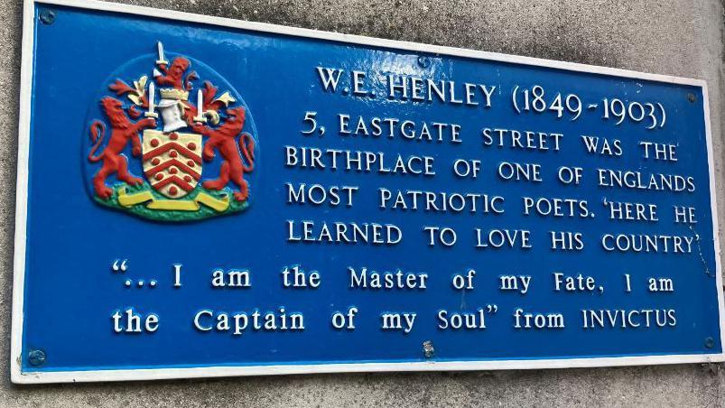 A blue plaque marking the birthplace of WE Henley in Gloucester. It has white text on the blue background. It contains the text "I am the master of my fate, I am the captain of my soul"