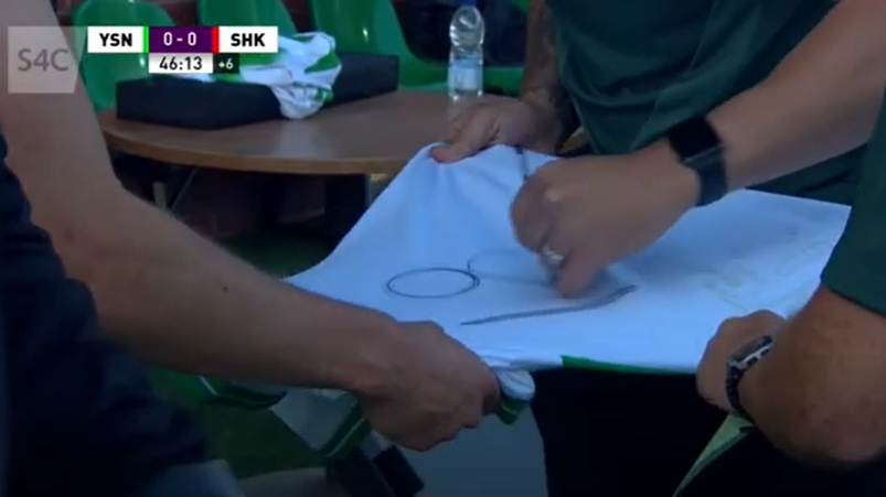 The New Saints staff write the number 18 on the back of a shirt