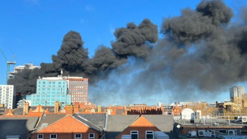 Black smoke billows across the blue sky over Reading.