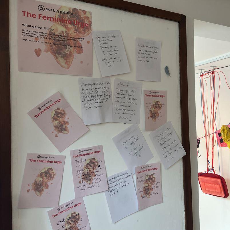 A black picture frame surrounds individual notes on pink and white paper, penned by women