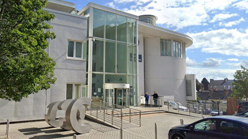 A light-coloured court building with a large floor to ceiling glass entrance way.
