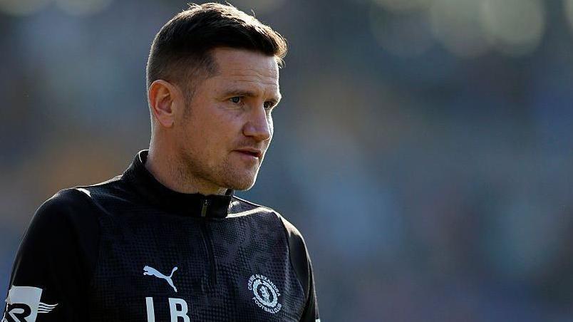 Crewe Alexandra manager Lee Bell watches on from the touchline during a game.