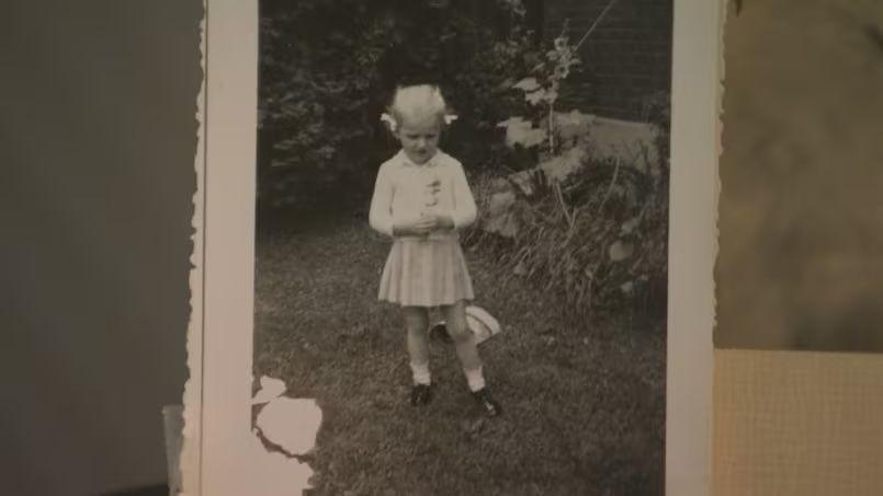 An old black-white photo of Lana Ponting as a little girl. She is in a light-coloured dress and her short blond hair is in pigtails.